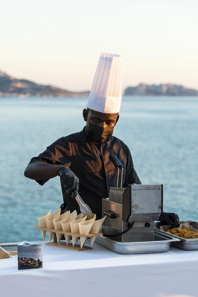 chef servant des cornets de friture sur fond de mer